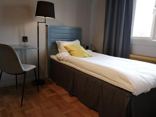 a bed with a blue headboard and a chair in a room at Hotell Apladalen i Värnamo in Värnamo