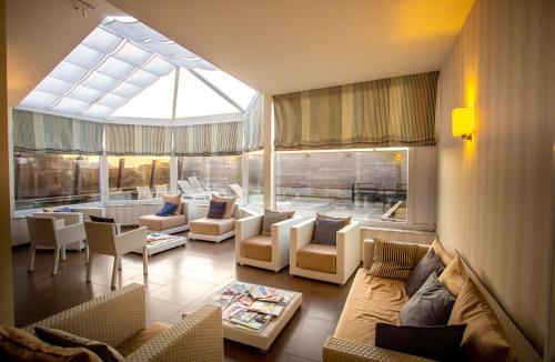 ein Wohnzimmer mit Sofas und Stühlen sowie einem großen Fenster in der Unterkunft Hotel Aazaert by WP Hotels in Blankenberge