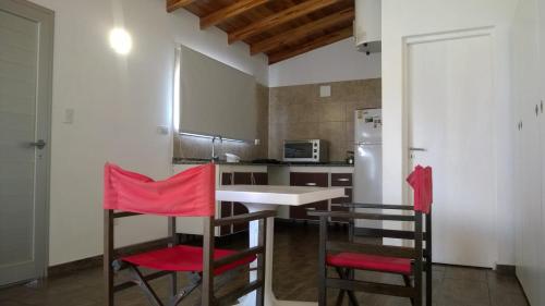 cocina con mesa y 2 sillas rojas en Verdeymar en Santa Clara del Mar