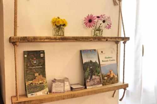a shelf with books and flowers on a wall at STECADÒ - Camera Lavanda in Dolceacqua