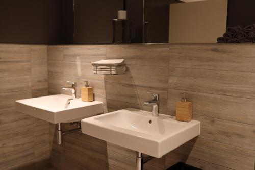 2 witte wastafels in een badkamer met houten wanden bij Ilvericher Hof in Meerbusch