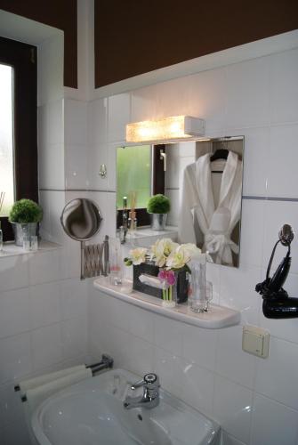 a white bathroom with a sink and a mirror at Landhotel Berggaststätte Bickenriede in Anrode