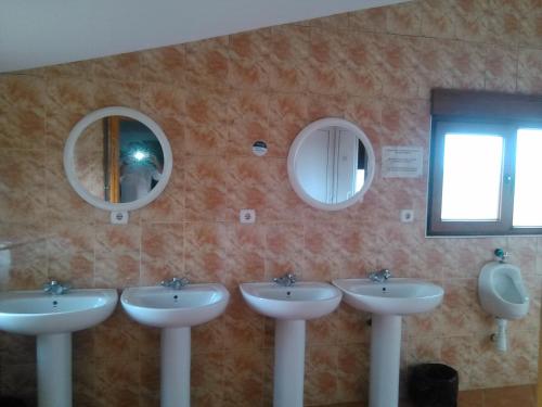 a bathroom with three sinks and mirrors on the wall at albergue camino real in Calzadilla de la Cueza