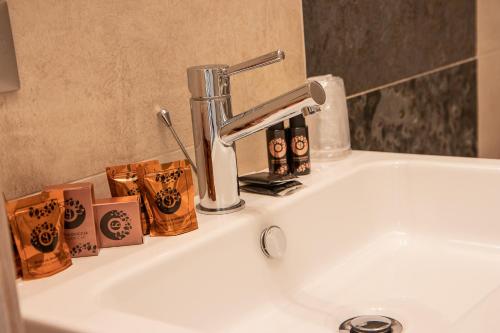 ein Waschbecken mit einem Wasserhahn und einigen Flaschen in der Unterkunft Hotel Corona in Tirano