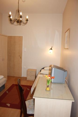 a room with a bed and a table with a television at Polus Pension in Sopron
