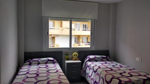 niewielka sypialnia z 2 łóżkami i oknem w obiekcie La Orquidea w mieście Benalmádena