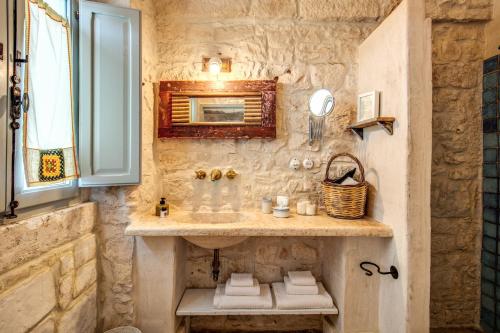 a stone bathroom with a sink and a mirror at Masseria Cervarolo in Ostuni