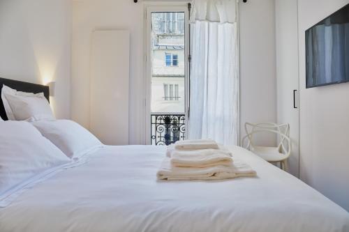 - un lit blanc avec des draps blancs et une fenêtre dans l'établissement RESIDENCES HARCOURT - Ile Saint Louis - PARIS, à Paris
