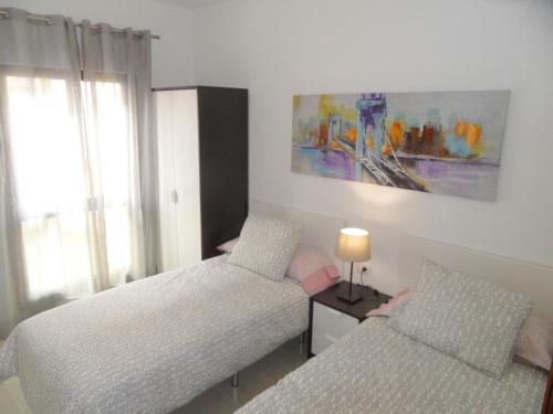 a bedroom with two beds and a table with a lamp at PLAYA SAN JUAN, Casa Vacacional CENTRICA in Playa de San Juan