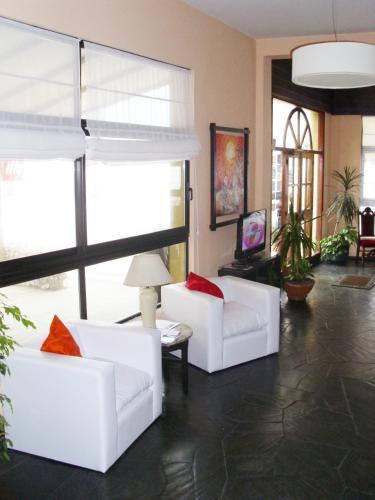 a living room with two white couches and a tv at Hotel City Piriápolis in Piriápolis