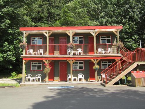a red house with white chairs and a deck at Holiday Motel & RV Resort in Hope