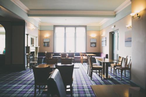 um restaurante com mesas e cadeiras num quarto em The Powfoot Hotel, Annan em Annan