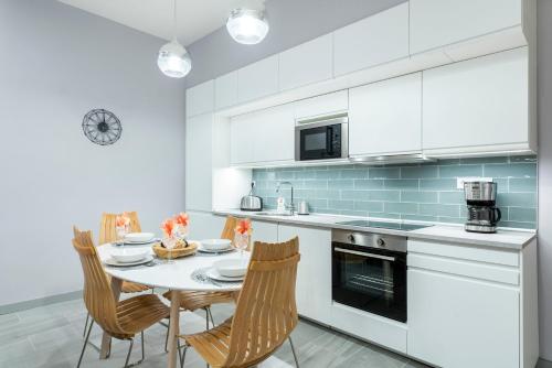 eine weiße Küche mit einem Tisch und Stühlen in der Unterkunft Modern 2 bedroom apartment with free airport transfer in Budapest