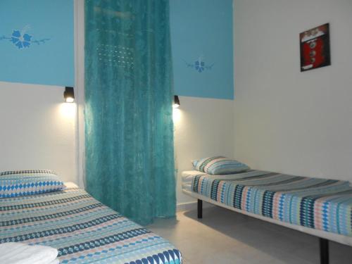リスボンにあるクレセント ルームズの青いカーテンが備わる客室のベッド2台