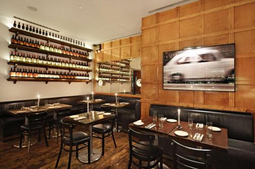 a dining room with tables and chairs and a tv at Gild Hall, A Thompson Hotel, by Hyatt in New York