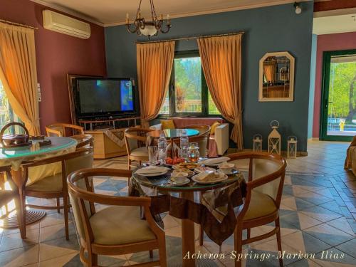 un soggiorno con tavolo, sedie e TV di Acheron Springs-Markou Ilias a Gliki