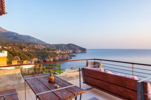 a table and bench on a balcony overlooking the ocean at Frictories station of residency in Limnionas