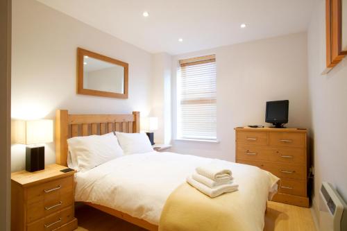 a bedroom with a bed and a dresser with a mirror at 2 bed 2 bath at Pelican Hse in Newbury - FREE secure, allocated parking in Newbury