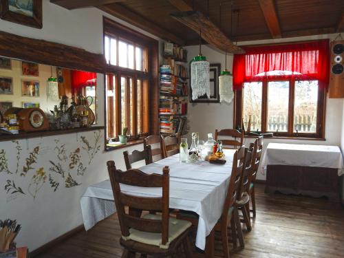 ein Esszimmer mit einem Tisch, Stühlen und Fenstern in der Unterkunft Łosinek in Dolistowo