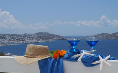 two glasses and a hat on a ledge with a view of the ocean at Amazing View Hotel Apartments in Agios Stefanos