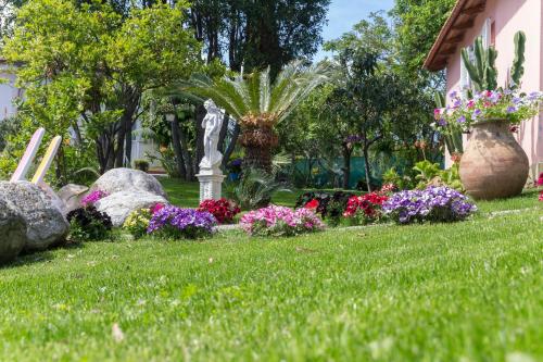 a garden with flowers and a statue in the grass at Le Villette di Villa Paola in Loano