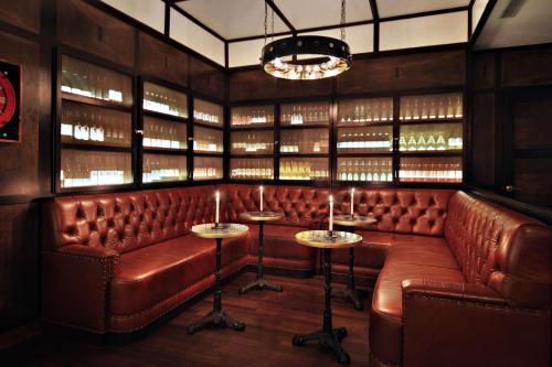 a bar with a brown leather bench and tables at Gild Hall, A Thompson Hotel, by Hyatt in New York