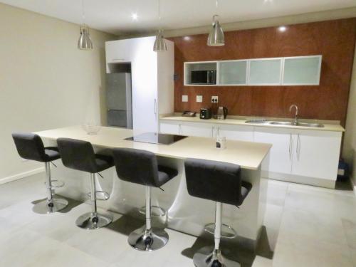 a kitchen with a island with black chairs in it at The Executive - Exclusive Self-Catering Apartments - Ezulwini in Ezulwini