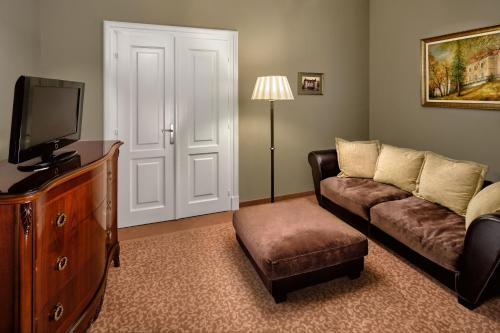 a living room with a couch and a tv at La Contessa Castle Hotel in Szilvásvárad