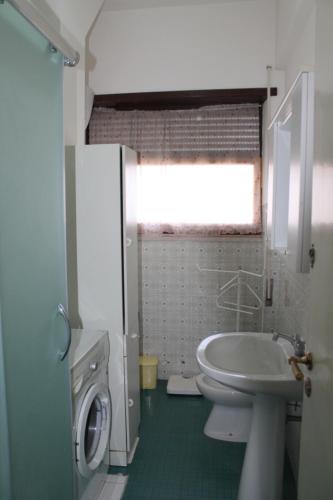 La salle de bains est pourvue d'un lavabo et d'un lave-linge. dans l'établissement Casa al Mare, à Torvaianica