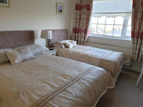 two beds in a room with a window at Glencora B&B in Skibbereen