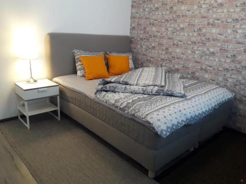 1 cama con almohadas de color naranja y pared de ladrillo en Hamina Orange Apartments Loft, en Hamina