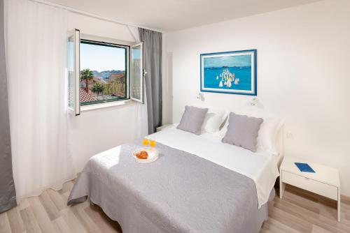 a white bedroom with a bed and a window at Apartment Adventure in Split