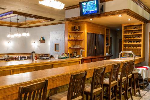 a kitchen with a bar with chairs and a television at Ramada by Wyndham Thunder Bay Airlane Hotel in Thunder Bay