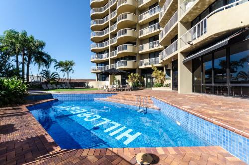 a swimming pool with a blue and white pool table and chairs at Hillcrest Apartment Hotel (formerly Central Hillcrest Apartments) in Brisbane