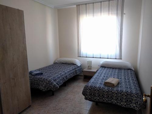 a small room with two beds and a window at Manzanera, junto Ayuntamiento y Riojaforum in Logroño