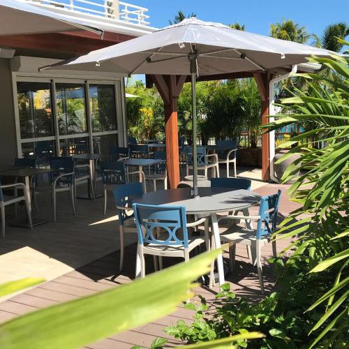 a patio with tables and chairs and an umbrella at Diamant les bains - Résidence Hôtelière in Le Diamant