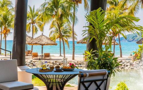 a table with food on a beach with palm trees at Thompson Zihuatanejo, A Beach Resort, by Hyatt in Zihuatanejo