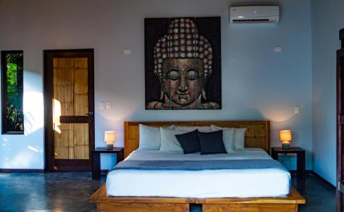 a bedroom with a king sized bed with a painting on the wall at Lua Villas in Santa Teresa Beach