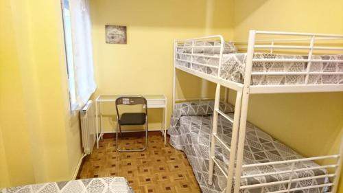 ログローニョにあるApartamento Riojanoの二段ベッド2台と椅子が備わる客室です。