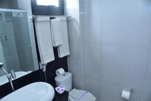 a bathroom with a sink and a toilet and towels at Hotel Village Confort Campina Grande in Campina Grande