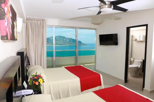 a bedroom with a bed and a view of the ocean at Las Flores Beach Resort in Mazatlán