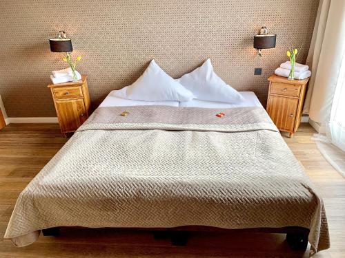 a bedroom with a large bed with two night stands at Hotel Akazienhof in Duisburg