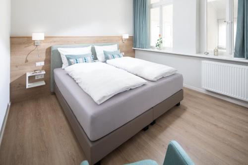 a bed with white sheets and blue pillows in a room at Fewo Ada in Norderney