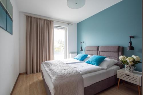 - une chambre avec un lit aux murs bleus et une fenêtre dans l'établissement Apartamenty Morski Florek, à Kołobrzeg