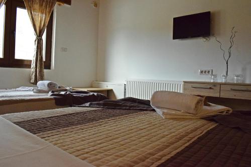 a bedroom with two beds and a tv on the wall at Resort Big House Plitvička jezera in Ličko Petrovo Selo