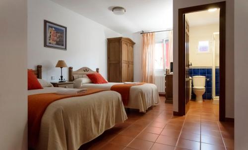 a hotel room with two beds and a bathroom at Habitaciones Casa Rural El Sauce in Nohales