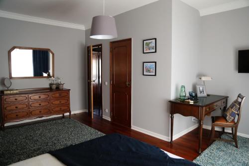 a room with a desk and a dresser and a mirror at Paradise Suites in Carcavelos