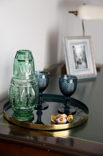 a green glass vase and three glasses on a table at Paradise Suites in Carcavelos