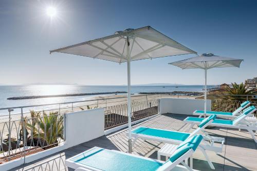 una terraza con sillas y sombrillas y la playa en Via Firenze 11 en Follonica