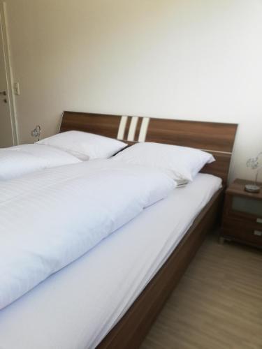 a bed with white sheets and a wooden head board at Gemütliches 3 Zimmer Apartment nahe Graz in Gratkorn